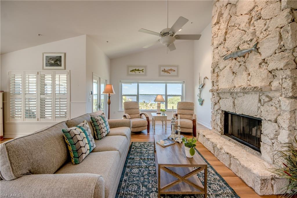Image 4: Living room featuring a stone fireplace, wood finished floors, ceiling fan, and lofted ceiling