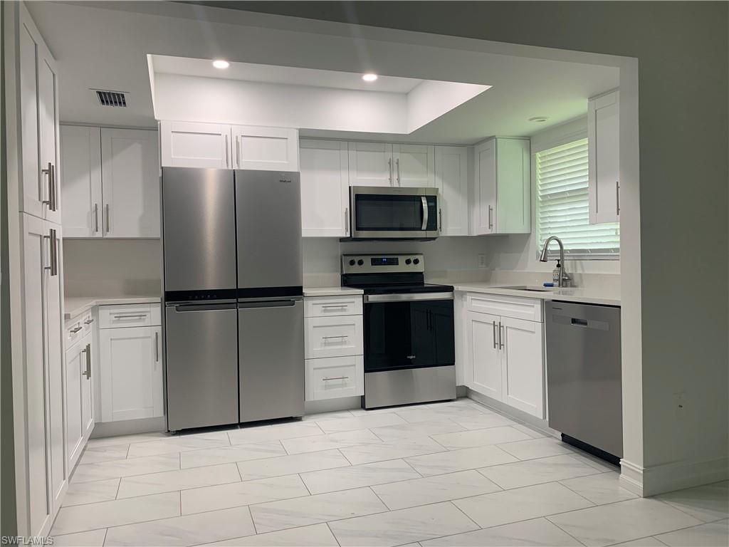 Image 4: Kitchen with appliances with stainless steel finishes, white cabinetry, light marble finish flooring, recessed lighting, and light stone countertops