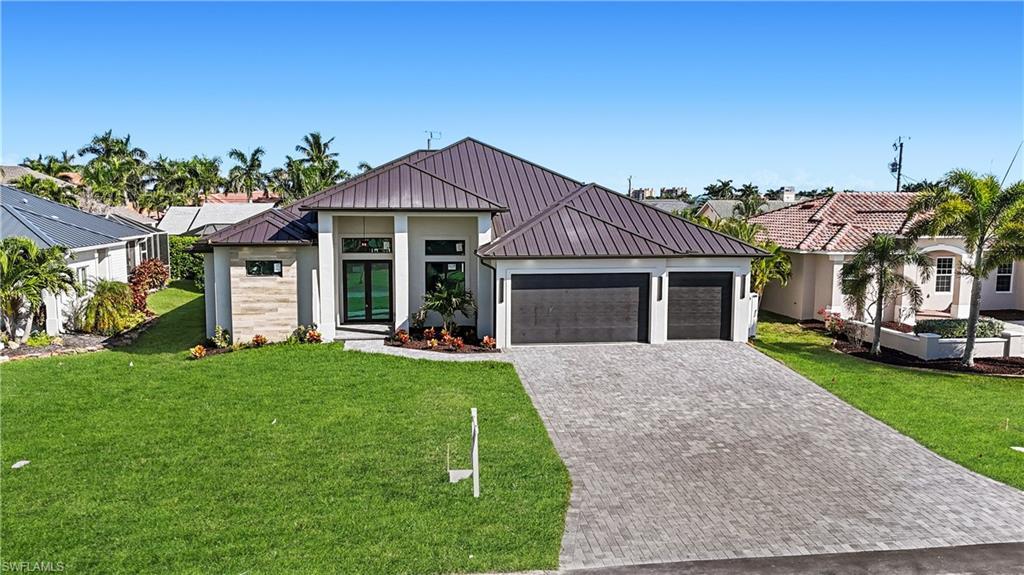 Image 2: View of front facade featuring a metal roof, a front lawn, a standing seam roof, decorative driveway, and an attached garage