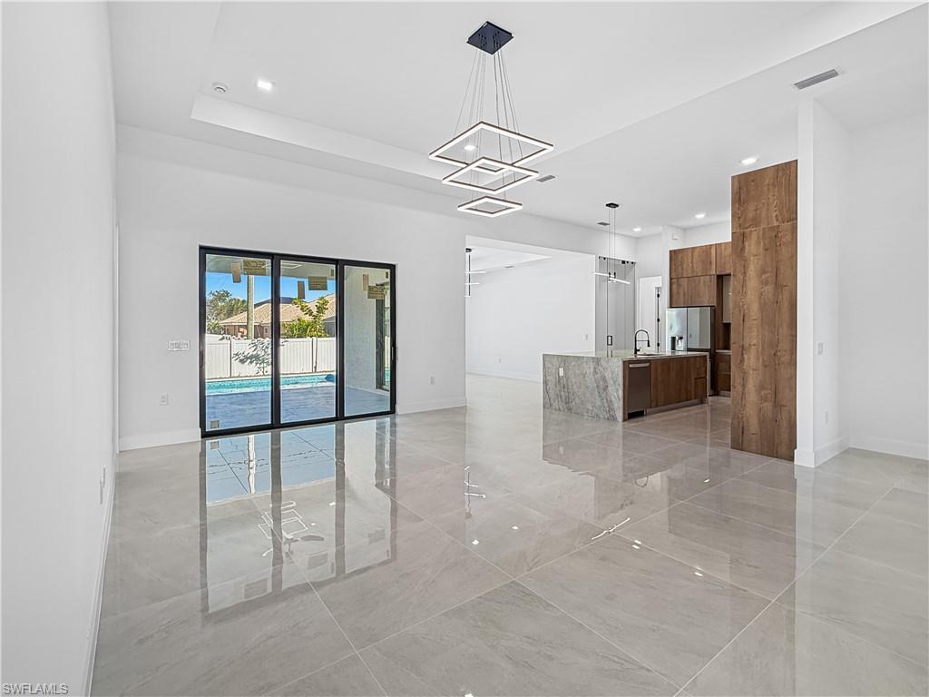 Image 4: Unfurnished living room featuring recessed lighting, a chandelier, and a tray ceiling