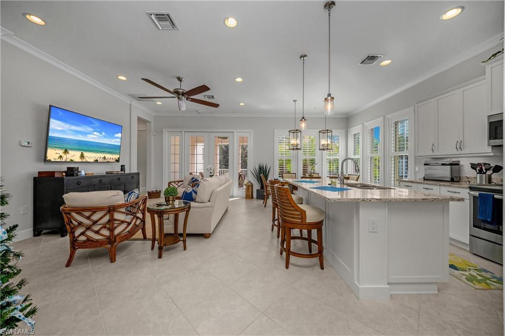 Image 3: Kitchen with open floor plan, white cabinetry, a breakfast bar, recessed lighting, and appliances with stainless steel finishes