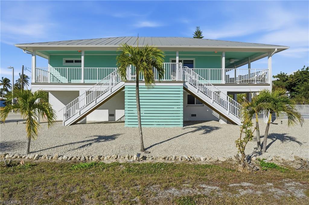 Image 2: View of front of home featuring stairway, a porch, and a metal roof - Virtually Edited Image