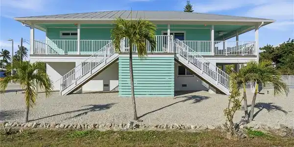 Image 2: View of front of home featuring stairway, a porch, and a metal roof - Virtually Edited Image