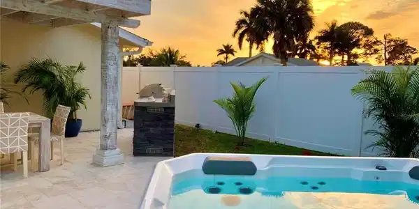 Image 3: Pool at dusk with a hot tub, a patio area, a fenced backyard, and outdoor dining space