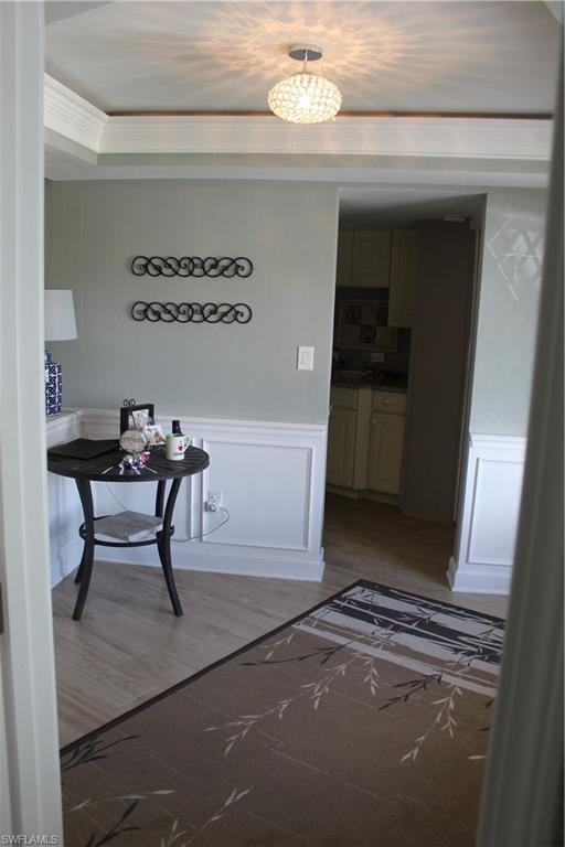 Image 4: Hall with wainscoting, light wood finished floors, a decorative wall, and ornamental molding