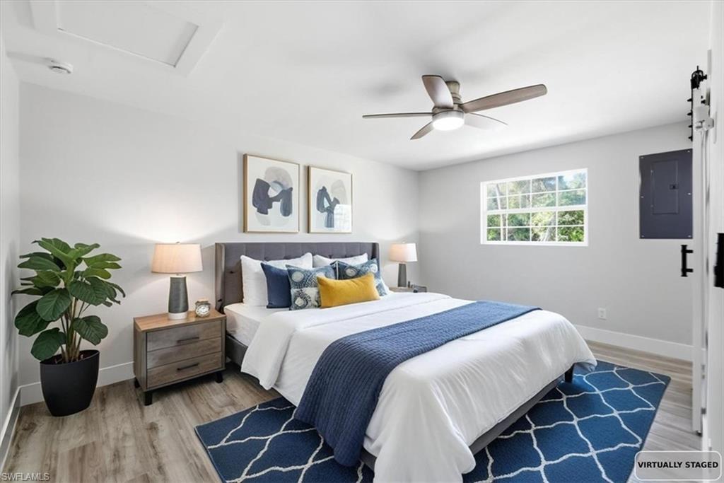 Image 4: Bedroom 2 with electric panel, light wood finished floors, and a ceiling fan virtually staged