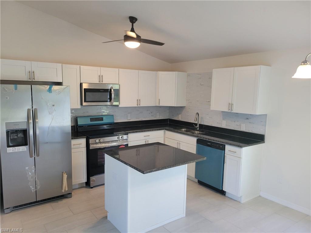Image 2: Kitchen with a kitchen island, stainless steel appliances, lofted ceiling, ceiling fan, and white cabinets