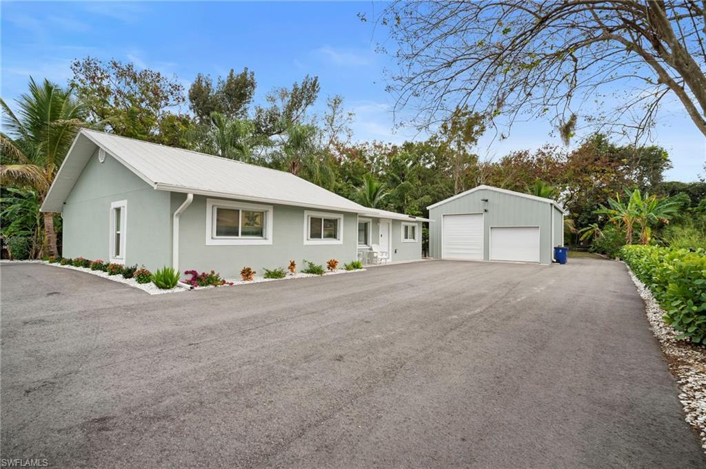 Image 1: Ranch-style home featuring an outbuilding, a garage, stucco siding, and a metal roof