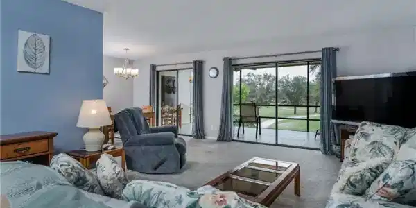 Image 3: Living room with a notable chandelier and light carpet