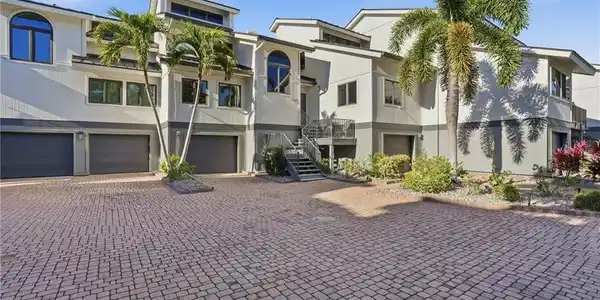 Image 2: View of building exterior featuring an attached garage, stairs, and driveway