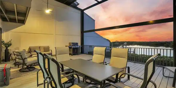 Image 3: Wooden deck featuring outdoor dining area, glass enclosure, area for grilling, a sunroom, and a water view