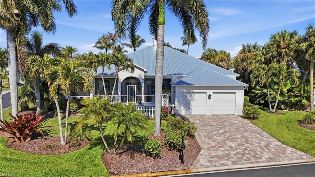Image 4: View of front of house with a front yard, driveway, a metal roof, and an attached garage