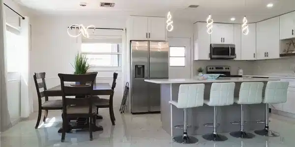 Image 2: Kitchen featuring stainless steel appliances, a kitchen breakfast bar, a kitchen island, two tone cabinetry, and tasteful backsplash