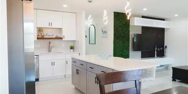 Image 3: Kitchen with freestanding refrigerator, hanging light fixtures, open shelves, backsplash, and light stone counters