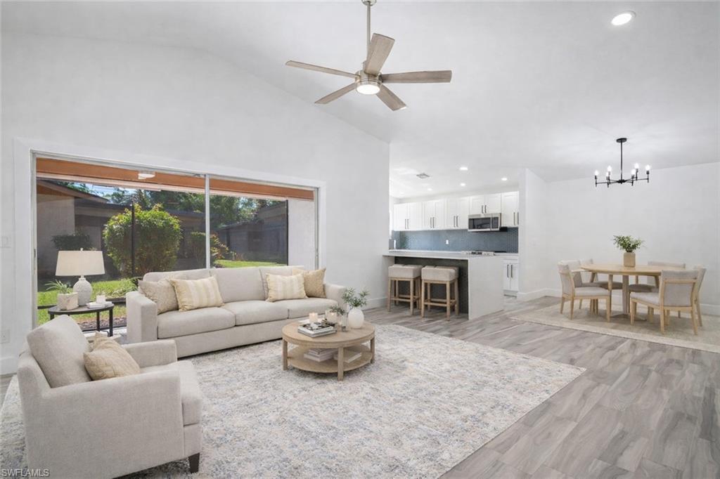 Image 1: Living room featuring a ceiling fan, light wood finished floors, vaulted ceiling, and a chandelier