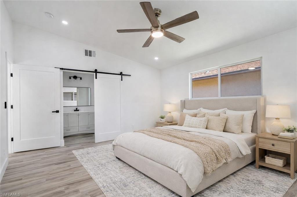 Image 2: Bedroom featuring a barn door, lofted ceiling, light wood finished floors, a ceiling fan, and recessed lighting