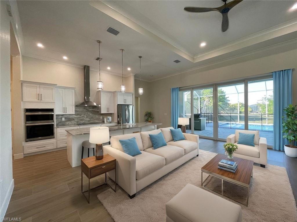Image 2: Living room with a tray ceiling, recessed lighting, a ceiling fan, ornamental molding, and light wood-type flooring