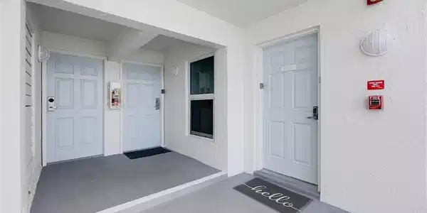 Image 2: View of exterior entry with a porch and stucco siding