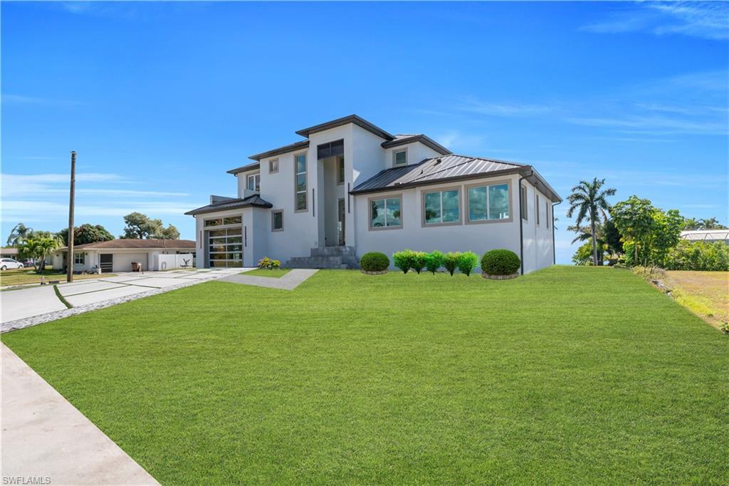 Image 3: View of front of house featuring a front yard, stucco siding, a garage, and driveway