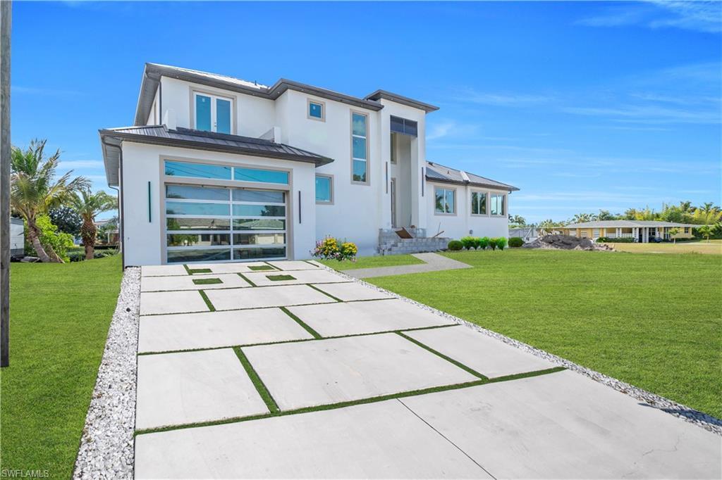 Image 4: Rear view of house featuring a yard, driveway, a standing seam roof, and a garage
