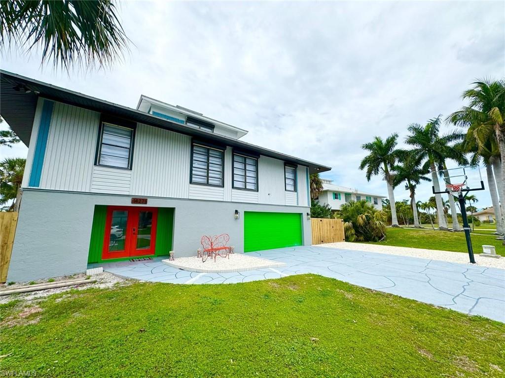 Image 2: Back of house featuring an attached garage, driveway, french doors, and stucco siding