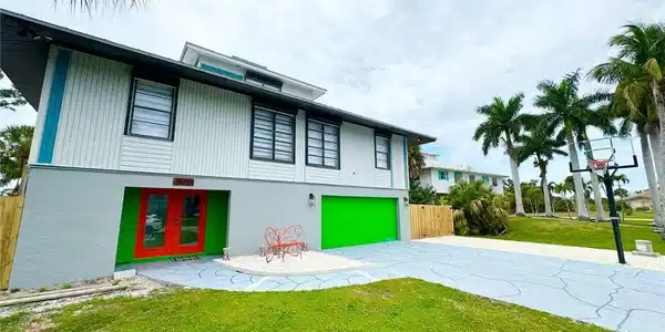 Image 2: Back of house featuring an attached garage, driveway, french doors, and stucco siding