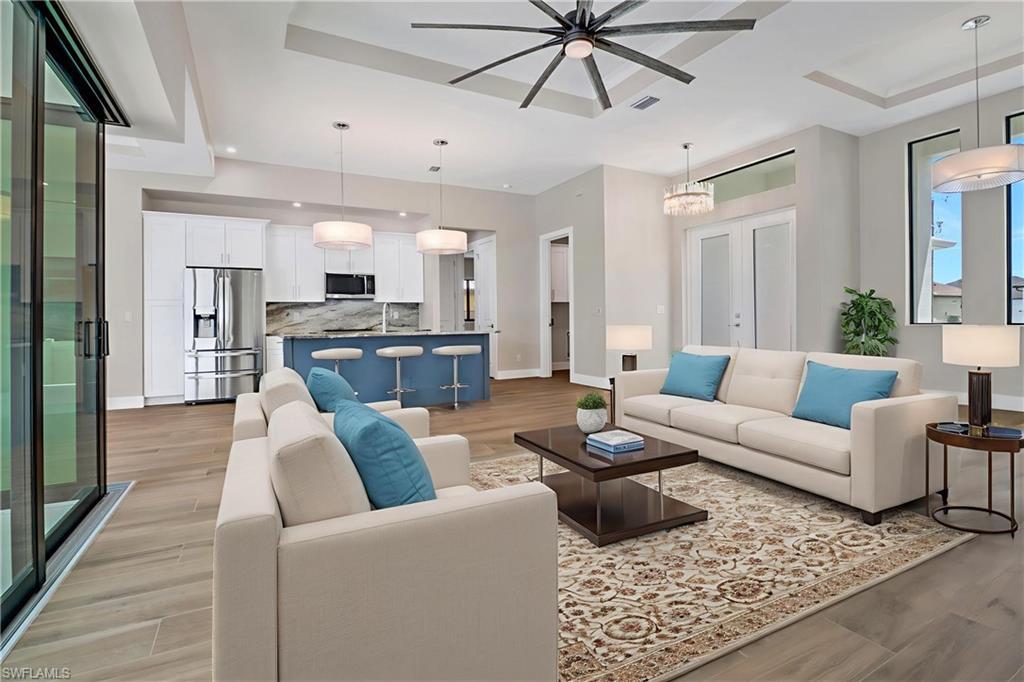Image 2: Living area with a ceiling fan, light wood finished floors, recessed lighting, and a raised ceiling