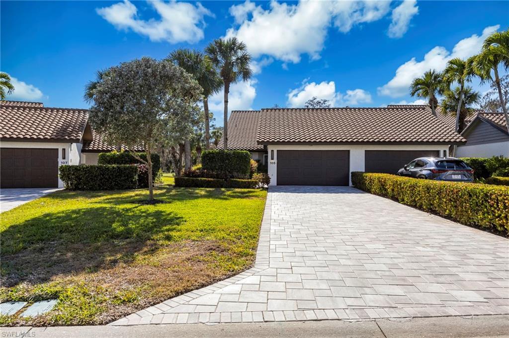 Image 2: View of front of house featuring stucco siding, a tiled roof, decorative driveway, a front lawn, and an attached garage