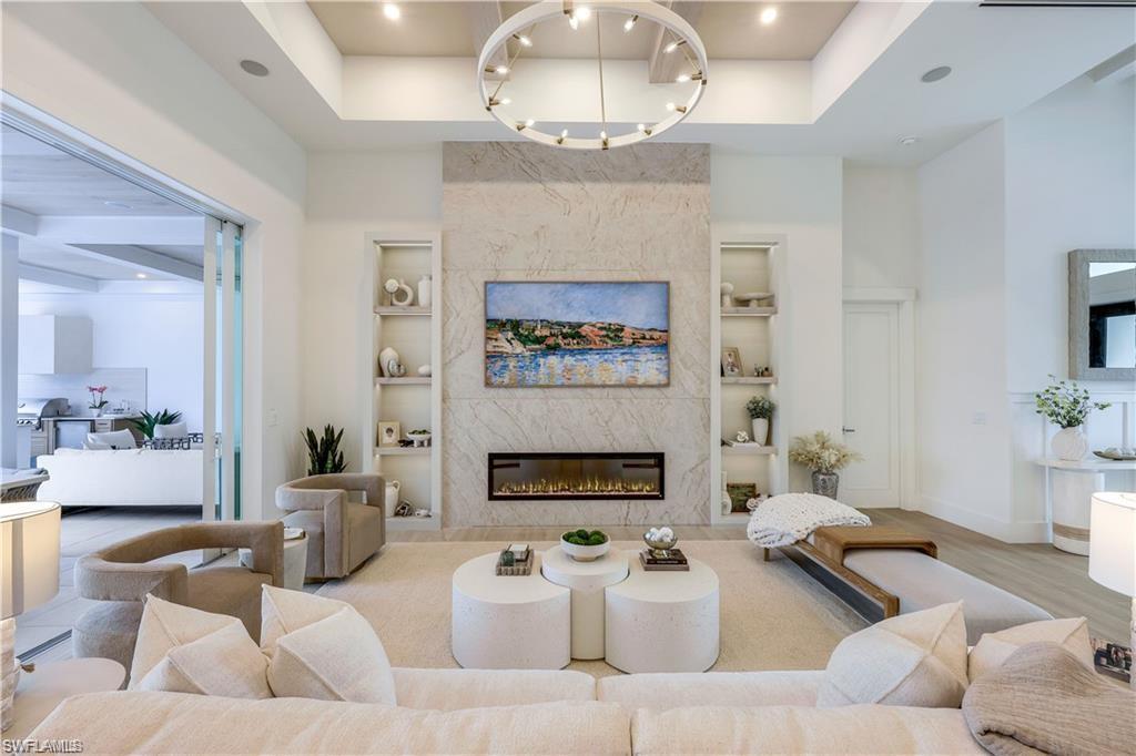 Image 1: Living area featuring a high end fireplace, recessed lighting, a high ceiling, and wood finished floors