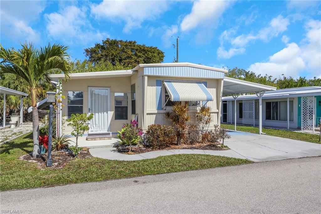Image 1: View of front of property featuring an attached carport, concrete driveway, and a front yard