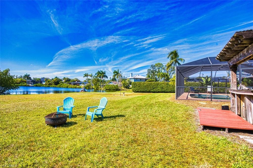 Image 2: View of grassy yard with a lanai, an outdoor pool, a fire pit, a sunroom, and a deck with water view