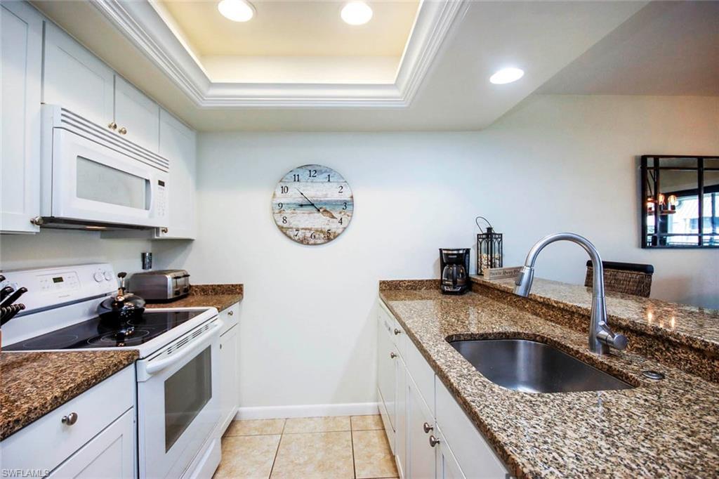 Image 3: Kitchen featuring white appliances, white cabinets, dark stone counters, recessed lighting, and a tray ceiling