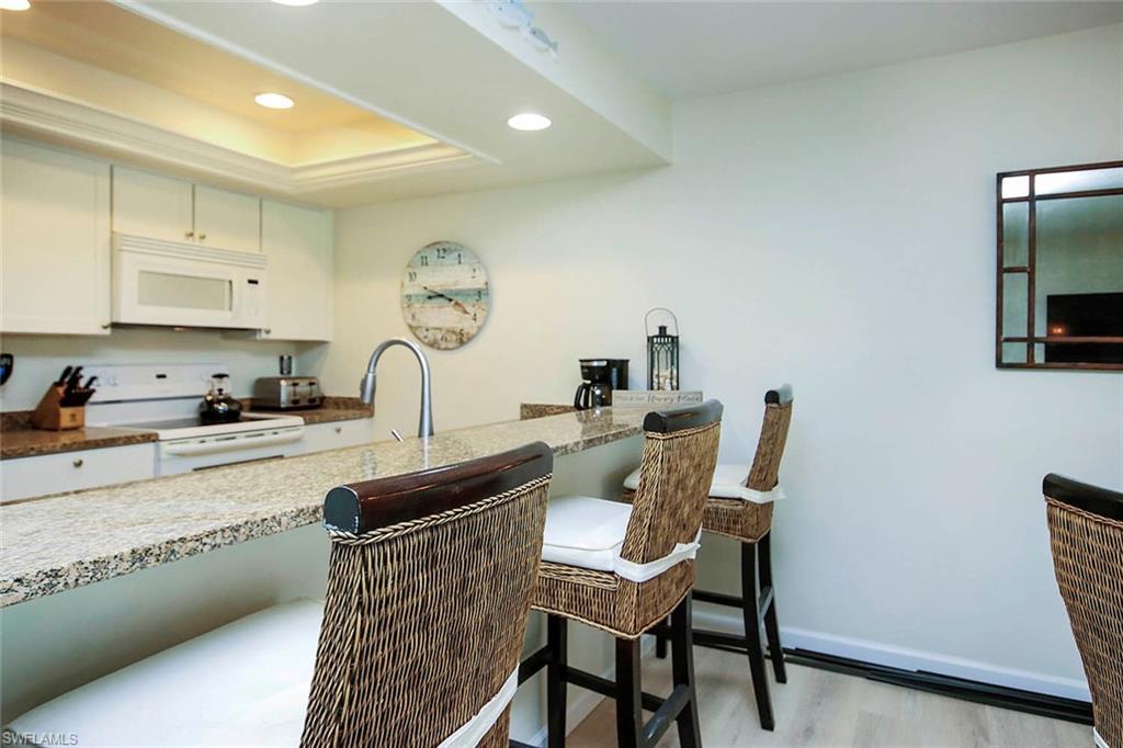 Image 4: Kitchen with white cabinetry, white appliances, recessed lighting, light stone countertops, and light wood-style flooring