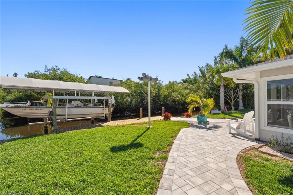Image 1: View of green lawn with boat lift, a boat dock, and a water view