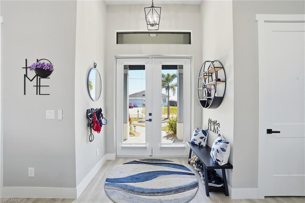 Image 2: Entrance foyer featuring french doors, a chandelier, and light wood finished floors