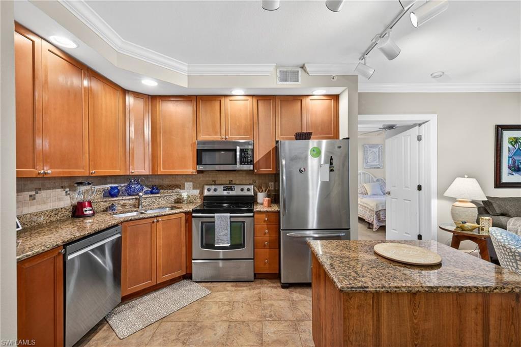Image 3: Kitchen with crown molding, dark stone countertops & stainless steel appliances