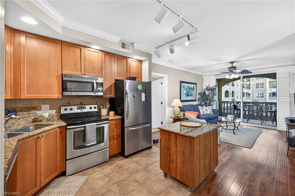 Image 4: Kitchen featuring crown molding, wood finish cabinets, stainless steel appliances, light stone counters, and track lighting