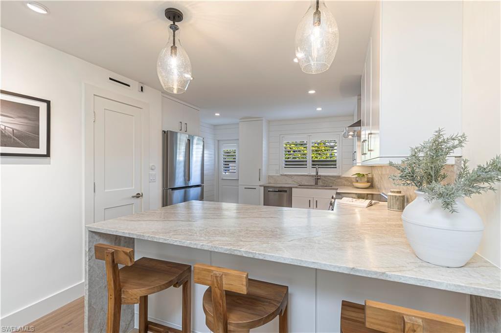 Image 4: Kitchen featuring decorative light fixtures, a breakfast bar area, appliances with stainless steel finishes, white cabinets, and a peninsula