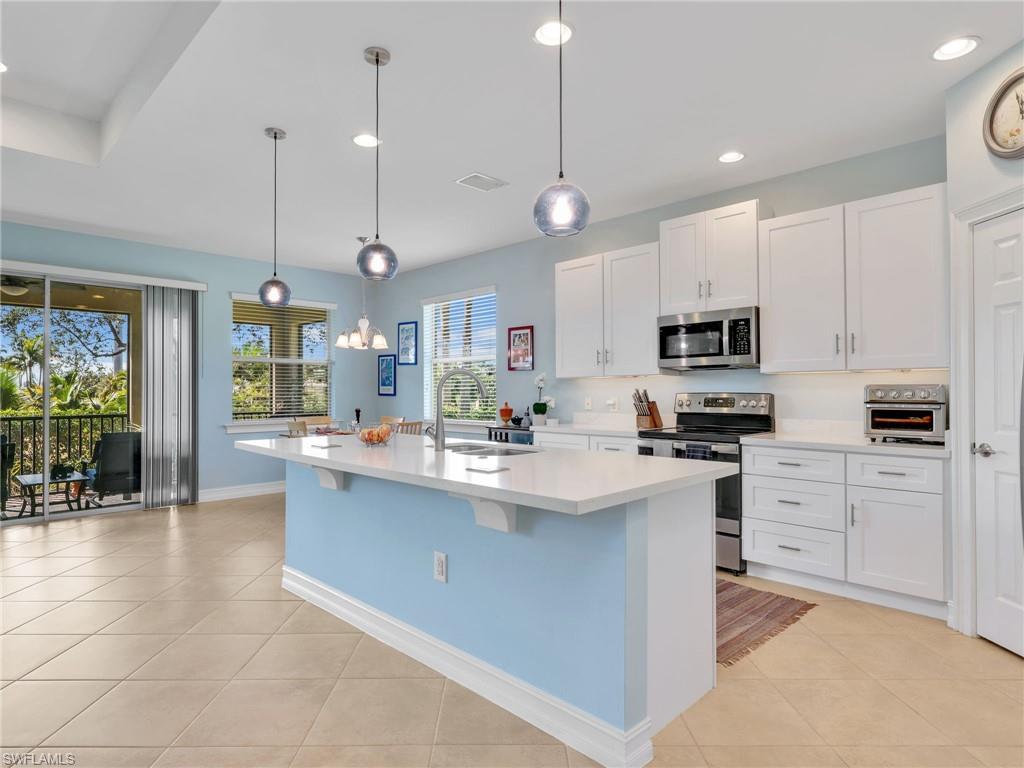Image 3: Kitchen with Island, Quartz Counters, Stainless Steel Appliances, and Stainless Steel Sink, Pantry, and Pendant Lighting