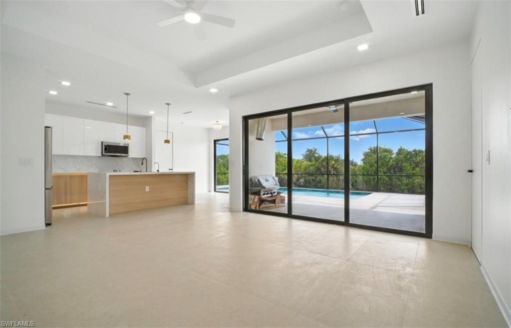 Image 3: Unfurnished living room featuring a ceiling fan, a sunroom, a tray ceiling, concrete floors, and recessed lighting