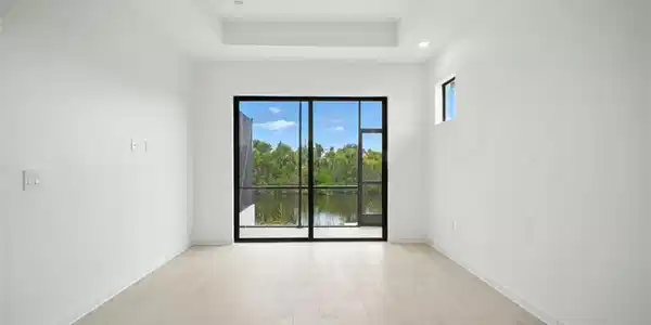 Image 4: Unfurnished room featuring light wood-style flooring, ceiling fan, a water view, and a raised ceiling