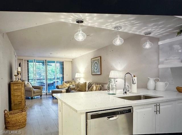 Image 3: Kitchen with dishwasher, pendant lighting, light stone counters, white cabinetry, and a peninsula