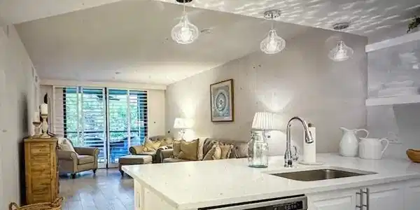 Image 3: Kitchen with dishwasher, pendant lighting, light stone counters, white cabinetry, and a peninsula