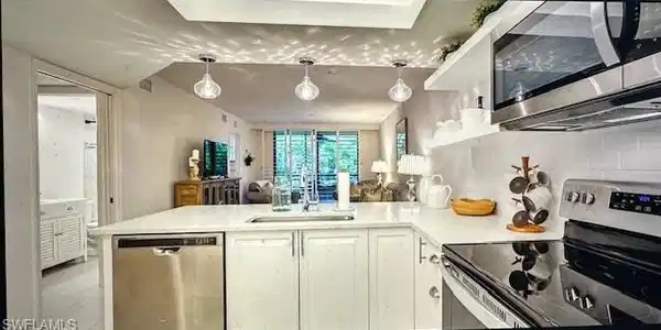 Image 4: Kitchen with stainless steel appliances, a peninsula, white cabinets, and hanging light fixtures