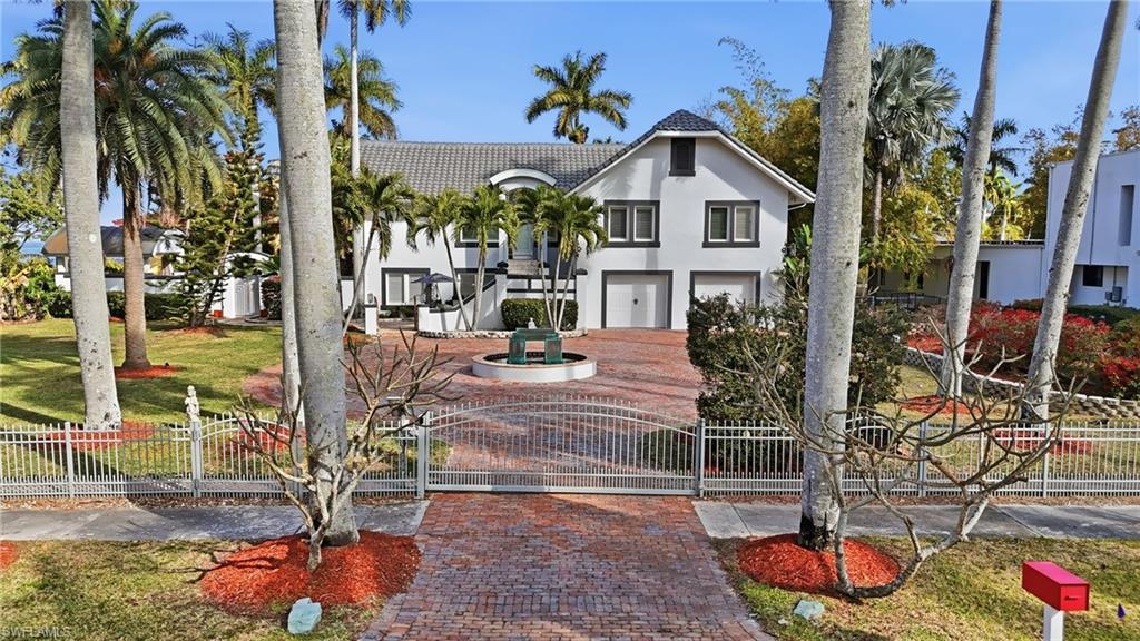 Image 2: View of front of home featuring a fenced front yard, a gate, stucco siding, an attached garage, and a tile roof