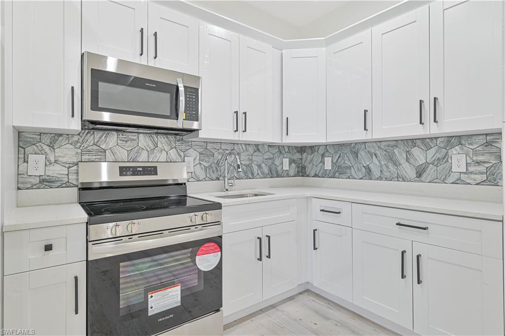 Image 4: Kitchen featuring light hardwood / wood-style flooring, stainless steel appliances, white cabinets, and tasteful backsplash
