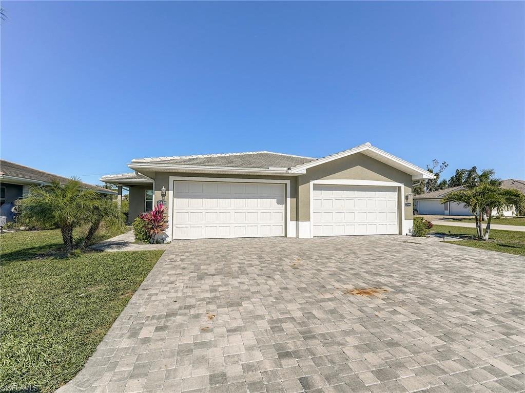 Image 4: View of front facade featuring a front yard, driveway, stucco siding, and a garage