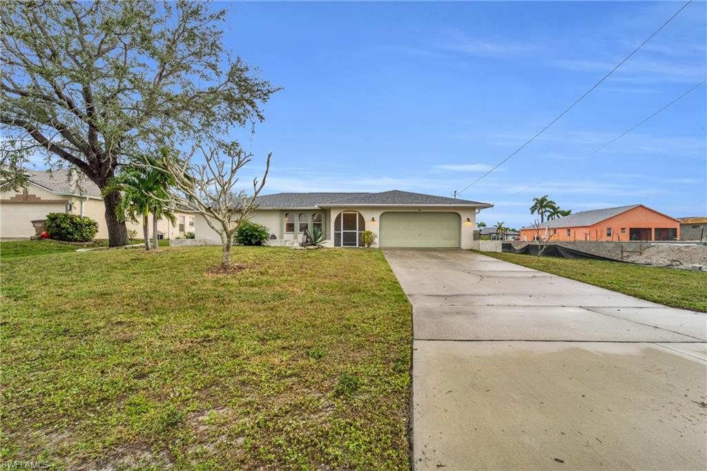 Image 2: Single story home with concrete driveway, stucco siding, and a garage