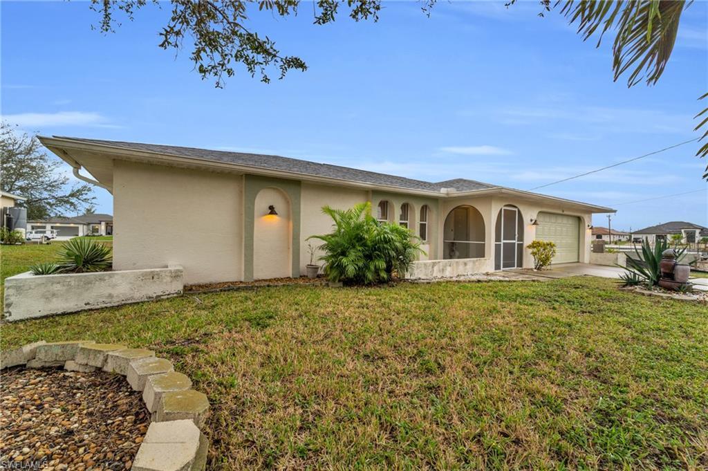 Image 4: View of front of house featuring stucco siding, a front yard, an attached garage, and driveway