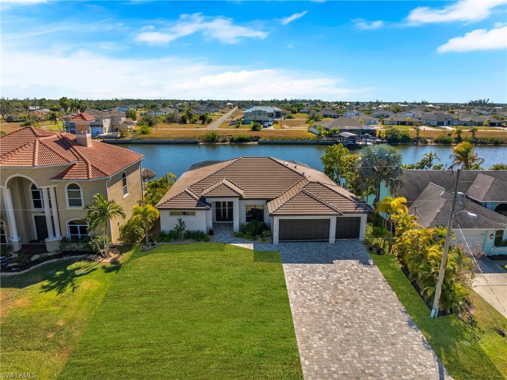 Image 2: View of front of house featuring a residential view, decorative driveway, stucco siding, a garage, and a water view